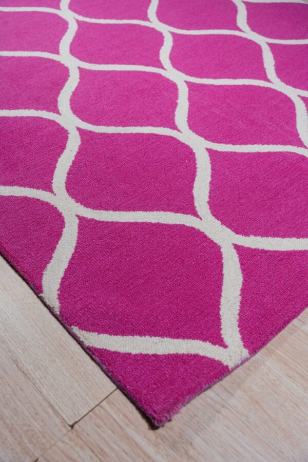 A vibrant pink rug with a cream lattice pattern rests on light blonde wood plank flooring.