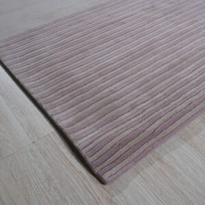 Dimensional high-pile rug with thick alternating pink and beige stripes rests on pale wood planks.