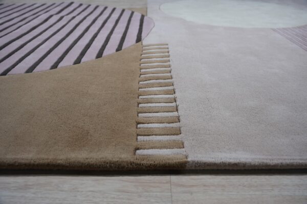 Abstract carved rug featuring dimensional stripes and color blocks in tan, mauve, and light gray on a wood floor.