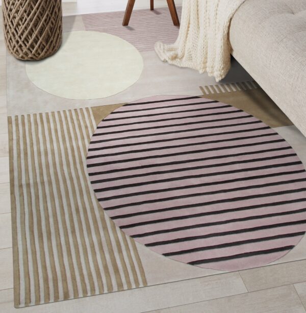 An abstract rug features stripes and circles in pink, black, tan, and cream tones on wood flooring.
