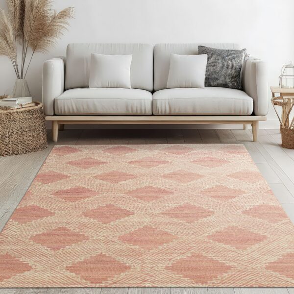 Rose and cream geometric rug on a light wood floor beneath a modern cream sofa.
