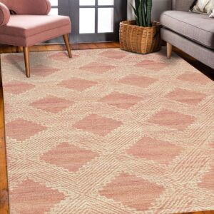 A dusty pink geometric rug lies on hardwood flooring between a pink armchair and a gray couch.