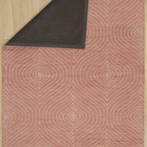 Dusty rose rug with light repeating diamond pattern, folded to show its dark backing on wood planks.