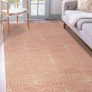 Coral and cream rug featuring concentric diamond shapes rests beneath a wood chair and gray sofa.