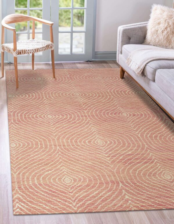 Coral and cream rug featuring concentric diamond shapes rests beneath a wood chair and gray sofa.