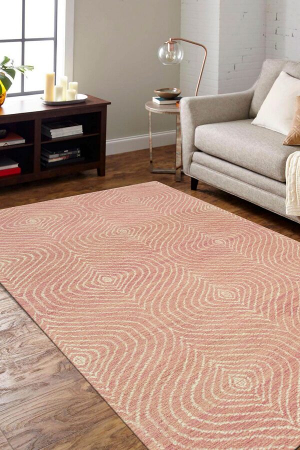 A low-pile pink and cream rug with a wavy concentric pattern is placed on wood floors near furniture.