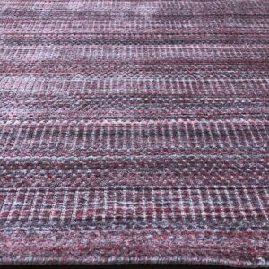 Textured burgundy and gray rug featuring alternating horizontal bands rests on light wood flooring.