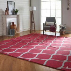Berry-red rug with a gray geometric wave pattern over hardwood floors in a bright room setting.