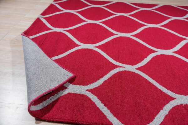 Deep red rug with a gray ogee pattern rests on light wood floor, showing the gray backing.