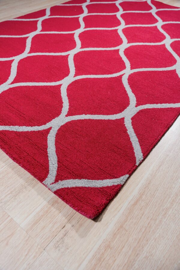 A red rug with a prominent gray geometric lattice pattern lies on light blonde wood flooring.