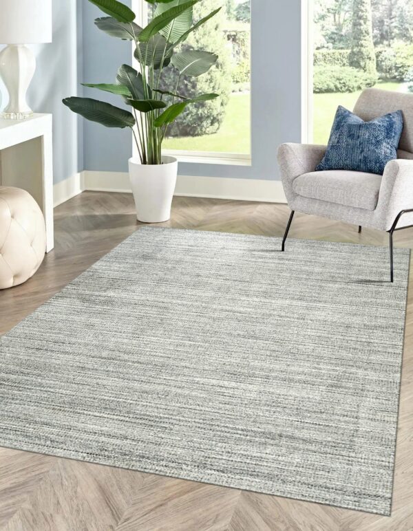 Light gray rug with horizontal linear texture on wood floors, framed by blue walls and a gray chair.