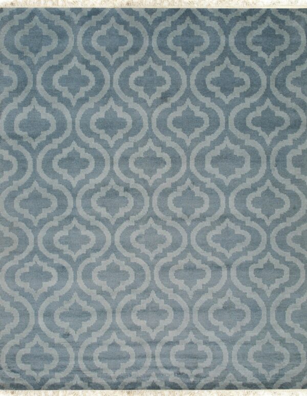 Muted blue pile rug featuring a repeating light blue geometric quatrefoil pattern and visible white fringe.
