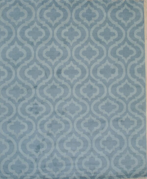 Light blue rug with tone-on-tone geometric ogee pattern laid flat on pale wood flooring.