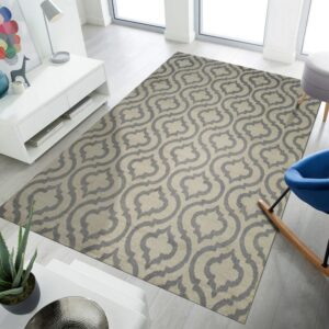 A gray and beige quatrefoil rug rests on light wood floors in a bright, modern room near a blue chair.
