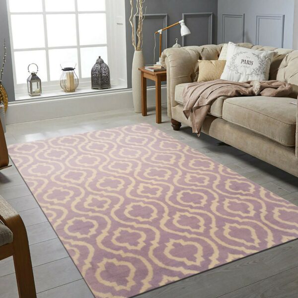 Lavender and cream geometric rug on light wood floors beside a tan sofa in a sunlit room.