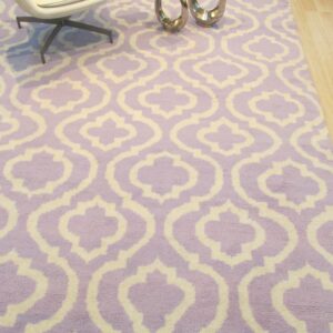 Plush purple and cream rug featuring a bold geometric trellis pattern on light wood flooring.