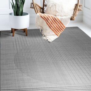 Gray rug featuring subtle embossed vertical stripes forming a large partial circle next to a wicker chair and plant.