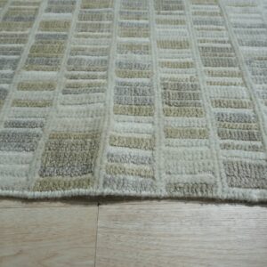 Geometric grid rug in textured cream, pale gray, and beige rests on light natural wood plank flooring.