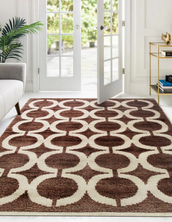 Brown and cream geometric area rug lies in a bright room with white furniture and open french doors.