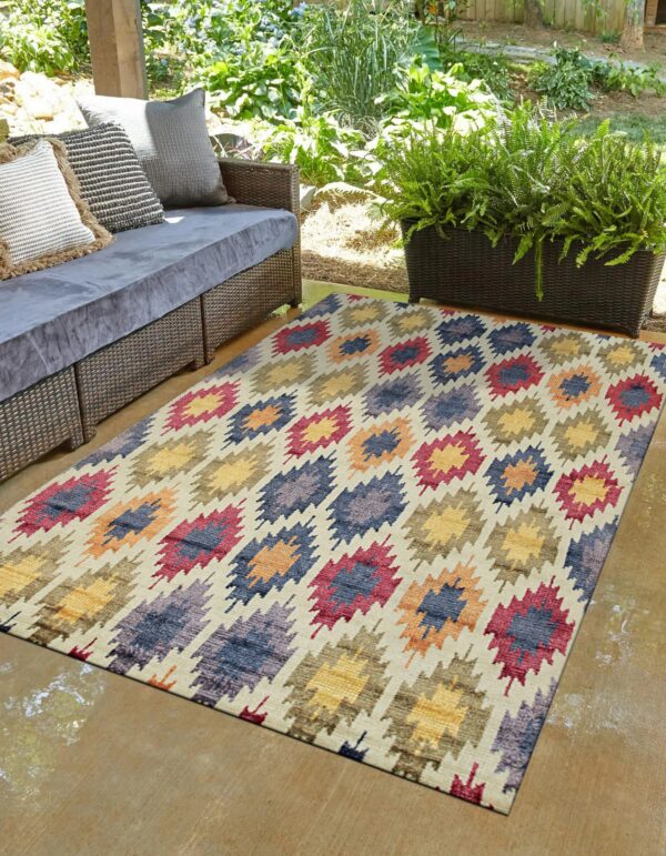 Multicolored geometric rug on a patio with a wicker sofa and lush green plants.
