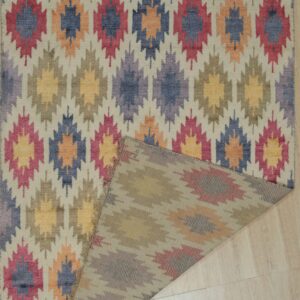 Multi-colored low-pile rug with repeated geometric diamond patterns folded over on pale hardwood floor.