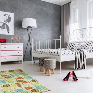 A low-pile rug with multi-colored owl pattern rests on a light floor in a modern gray and white bedroom.