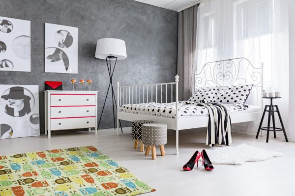 A low-pile rug with multi-colored owl pattern rests on a light floor in a modern gray and white bedroom.