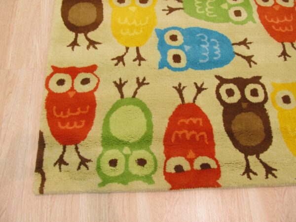 Medium pile rug with a multicolor owl pattern in red, yellow, green, and blue on light wood planks.