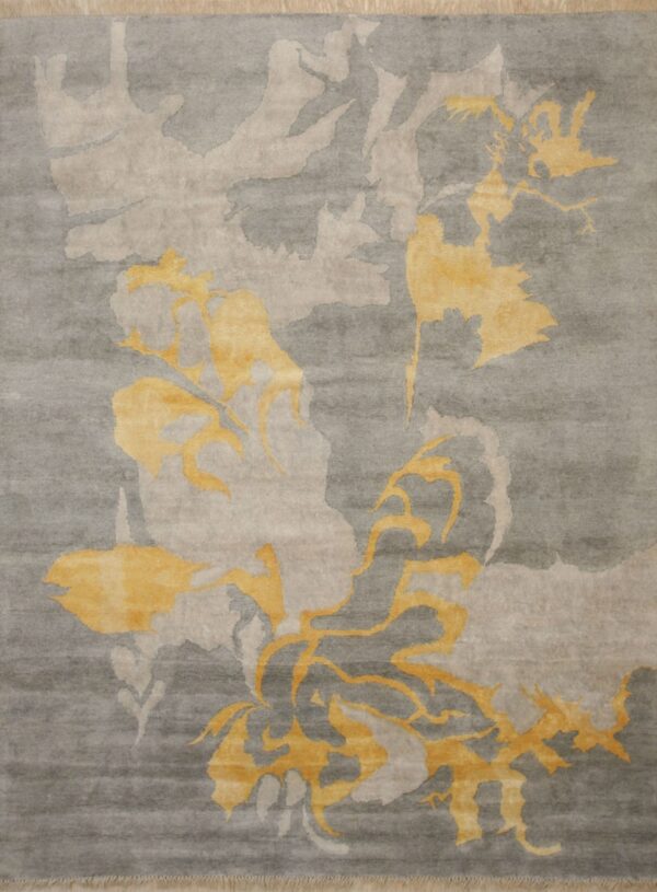 A low-pile gray rug with carved abstract patterns in light beige and golden yellow motifs.