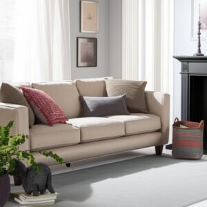 Light grey area rug with a subtle texture placed beneath a cream-colored sofa and dark fireplace.