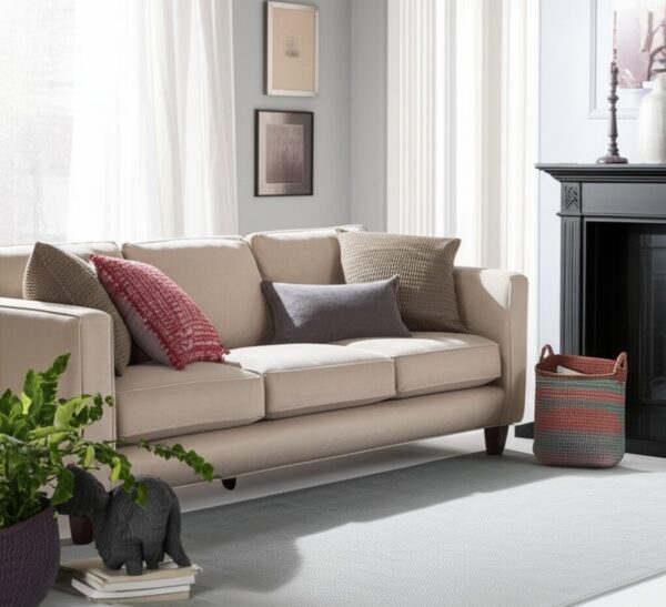 Light grey area rug with a subtle texture placed beneath a cream-colored sofa and dark fireplace.