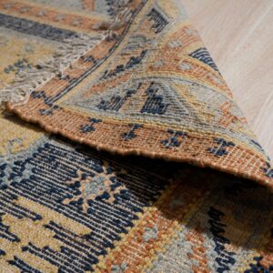 Low-pile rug with geometric patterns in navy, yellow, and orange folded on light wood flooring.