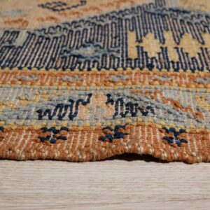 Woven rug detail showing navy, yellow, rust, and blue patterned bands resting on light wood flooring.