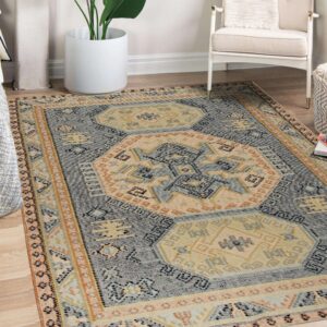 Flatwoven geometric rug in blue, tan, and terracotta colors sits on wood flooring.