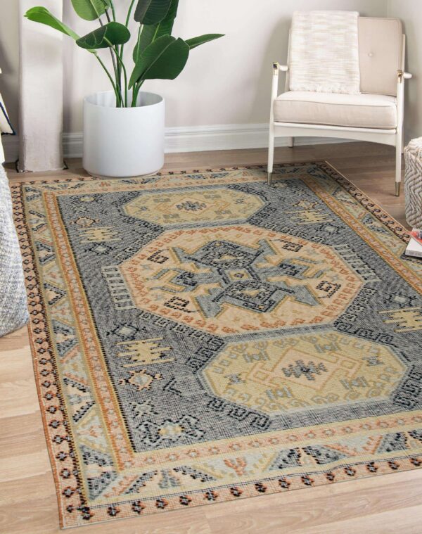 Flatwoven geometric rug in blue, tan, and terracotta colors sits on wood flooring.
