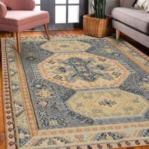 Blue, cream, and orange flat weave rug featuring geometric medallions next to pink and gray seating.