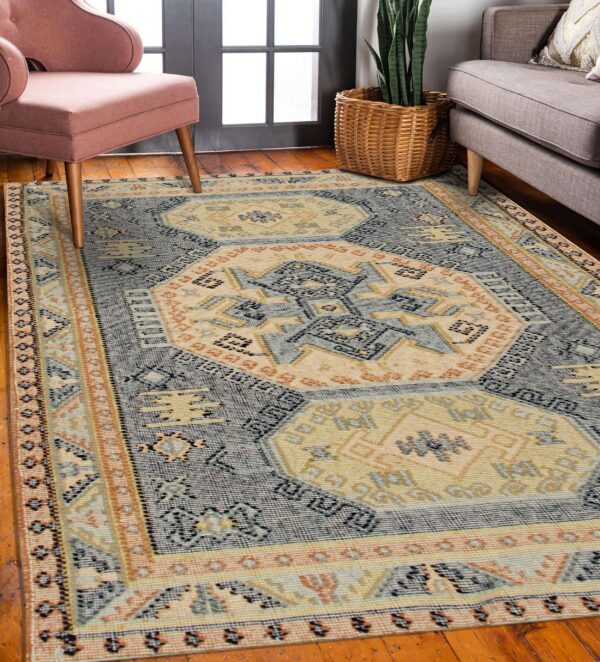 Blue, cream, and orange flat weave rug featuring geometric medallions next to pink and gray seating.