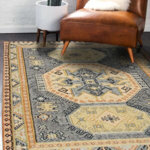 Gray and cream geometric rug with orange accents anchors a leather armchair on dark wood flooring.
