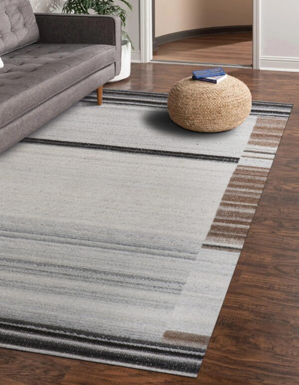 Abstract low-pile rug with light gray, charcoal, and brown horizontal stripes on dark wood flooring.