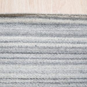 Low-pile rug with alternating heather gray and light gray horizontal stripes on a wood floor.