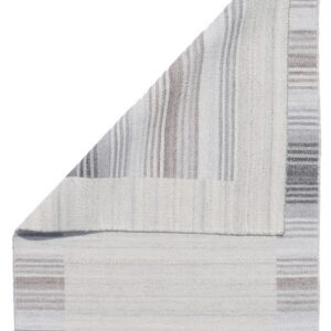 Neutral flatwoven rug folded over, revealing contrasting vertical and horizontal gray and white stripes.