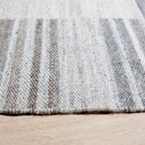 Close-up of a low-pile gray and white striped rug texture resting on light blonde wood flooring.