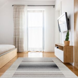 White, gray, and brown striped flatweave rug centered on light wood flooring in a bright modern room.