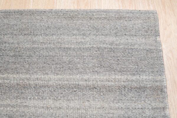 Heathered gray rug with faint horizontal bands displayed on light-toned plank flooring.