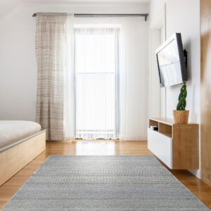 Gray and white woven texture rug centered on hardwood flooring in a bright modern room.
