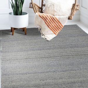 A flatwoven gray heathered rug is placed under a wicker chair and white plant stand on a white floor.