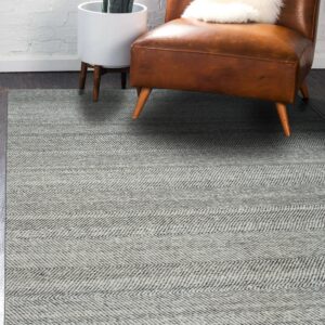Light and dark gray chevron rug on wood flooring, next to a brown leather chair and houseplant.