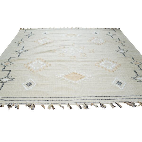 Beige flatweave rug with black, white, and tan geometric diamond patterns and tassels.