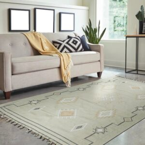 A light green flatweave rug featuring geometric patterns lays beneath a sofa in a bright room.