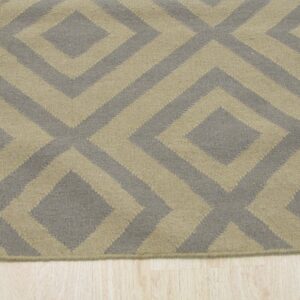 Low-pile geometric rug in tan and grayish-brown diamond pattern rests on light wood flooring.